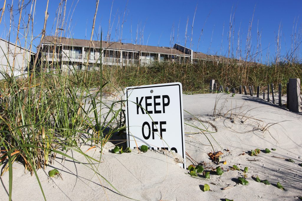 An old wooden sign at Atlantic Beach warns people to keep off the dunes to protect the fragile ecosystem. (photo by Mary Lide Parker)