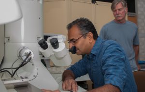 Amar Kumbhar peers through a transmission electron microscope as Professor Greg Forest looks on. 