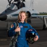 Carolina alumna Zena Cardman stands on a tarmac holding her gear. She is a new NASA astronaut trainee. Over 18,000 people applied to be in the 2017 class; she was one of 12 selected.