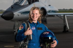 Carolina alumna Zena Cardman stands on a tarmac holding her gear. She is a new NASA astronaut trainee. Over 18,000 people applied to be in the 2017 class; she was one of 12 selected.